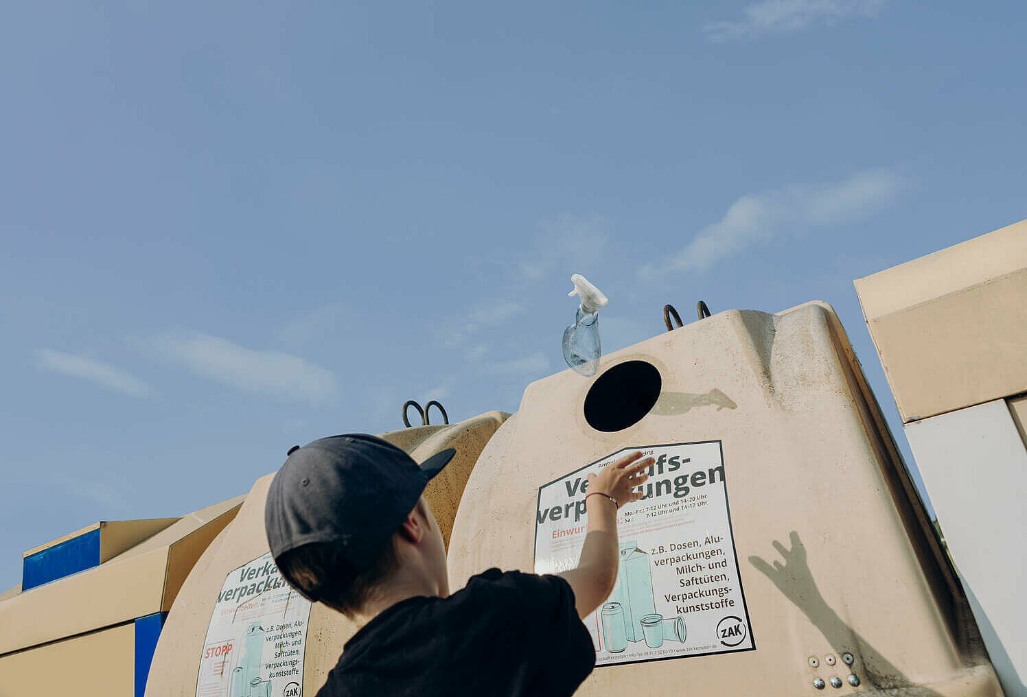 Ein Junge wirft eine Kunststoffverpackung den Container für Verkaufsverpackungen. 