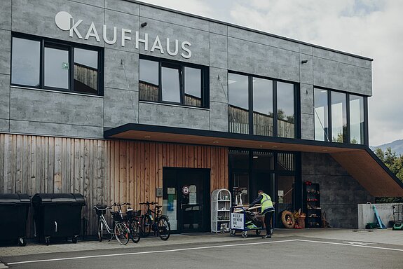 Vor dem Gebäude des ZAK Kaufhauses steht ein Mitarbeiter mit einem blauen Transportwagen