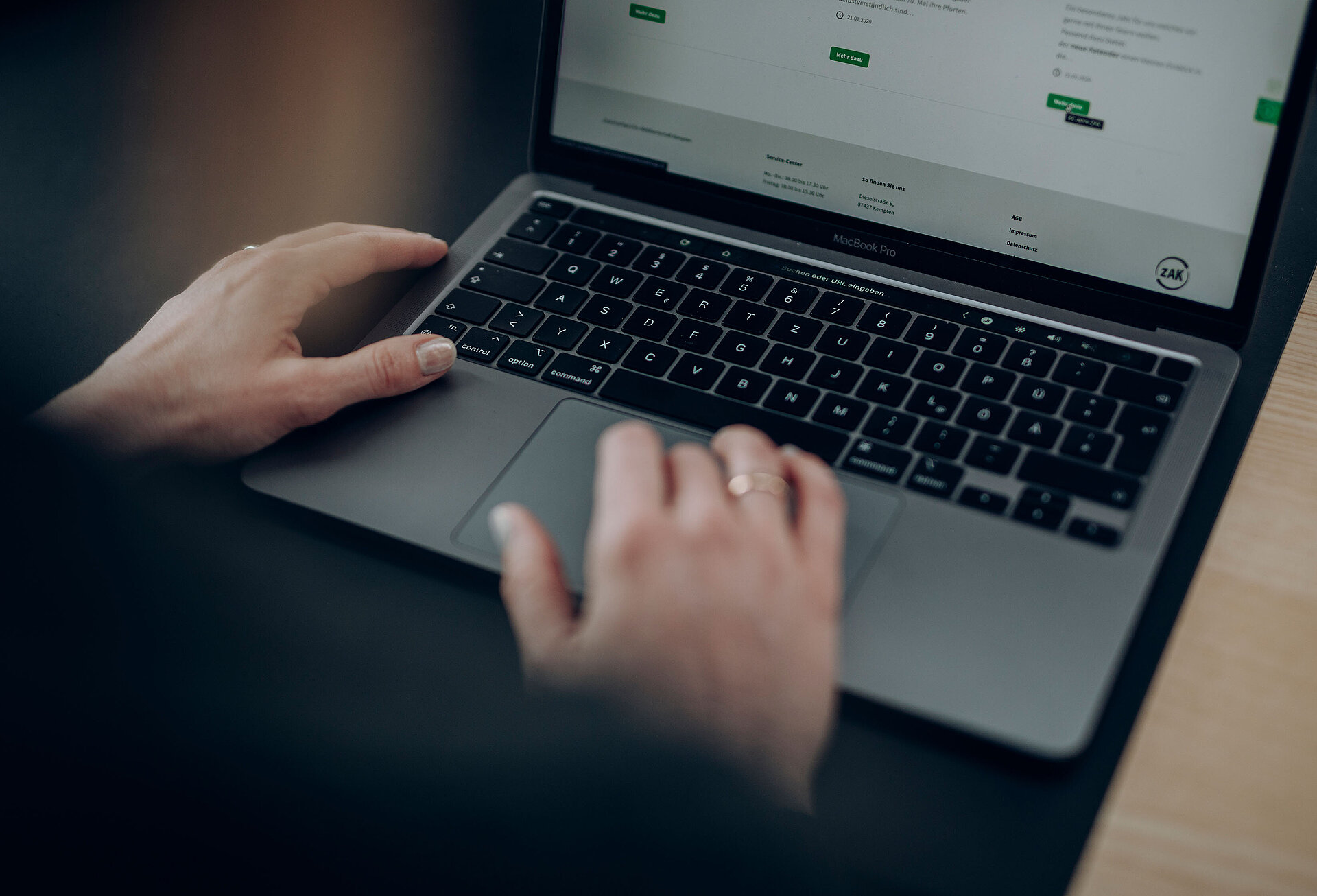 Person sitzt am Laptop und scrollt durch die ZAK-Website